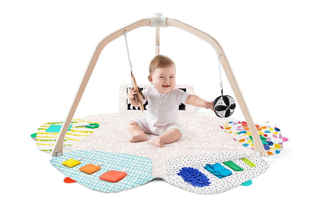 Baby playing with a colorful play gym on a white background