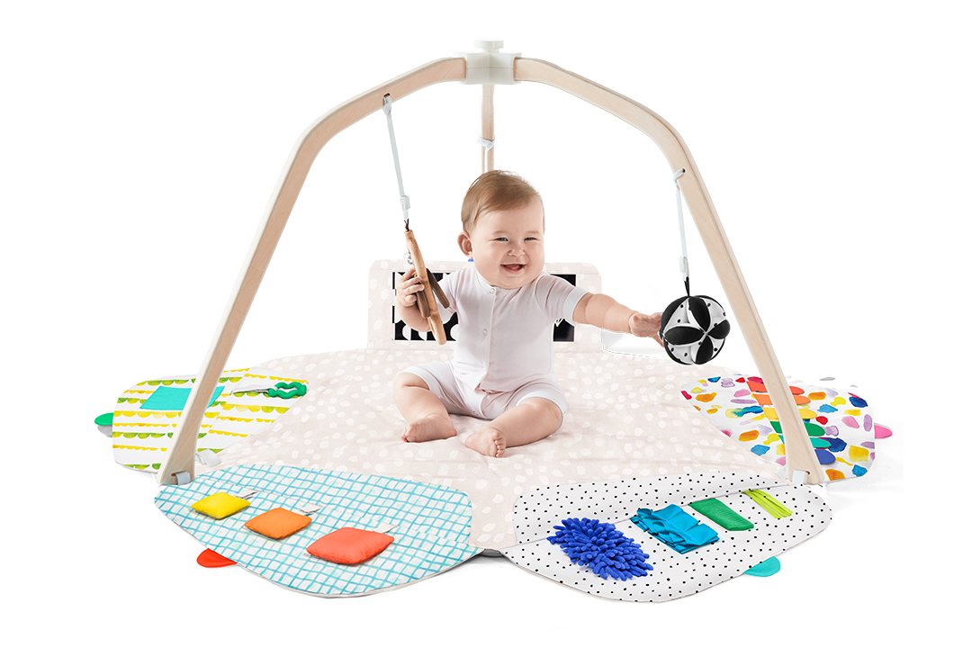 Baby playing with a colorful play gym on a white background