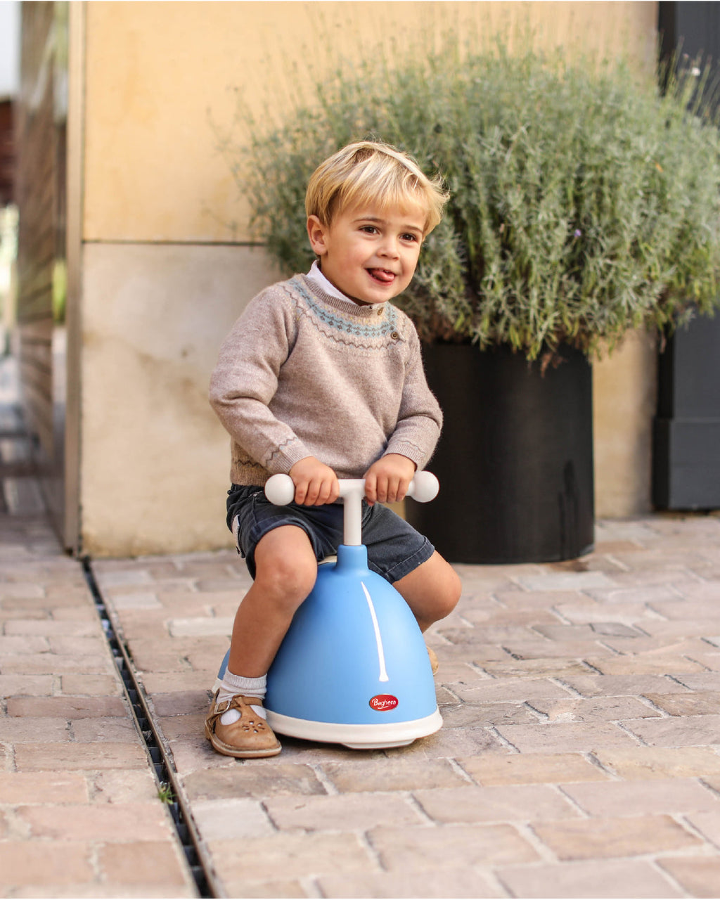 Child sitting on a blue baghera twister ride-on toy outdoors