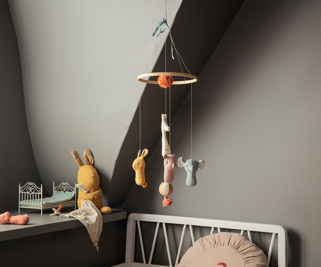 Children's room with a hanging toy mobile and toys on a shelf.