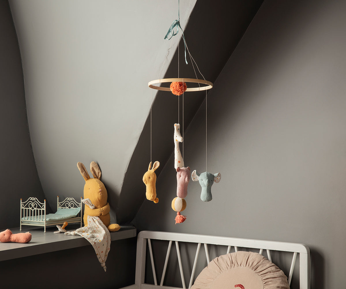 Children's room with a hanging toy mobile and toys on a shelf.