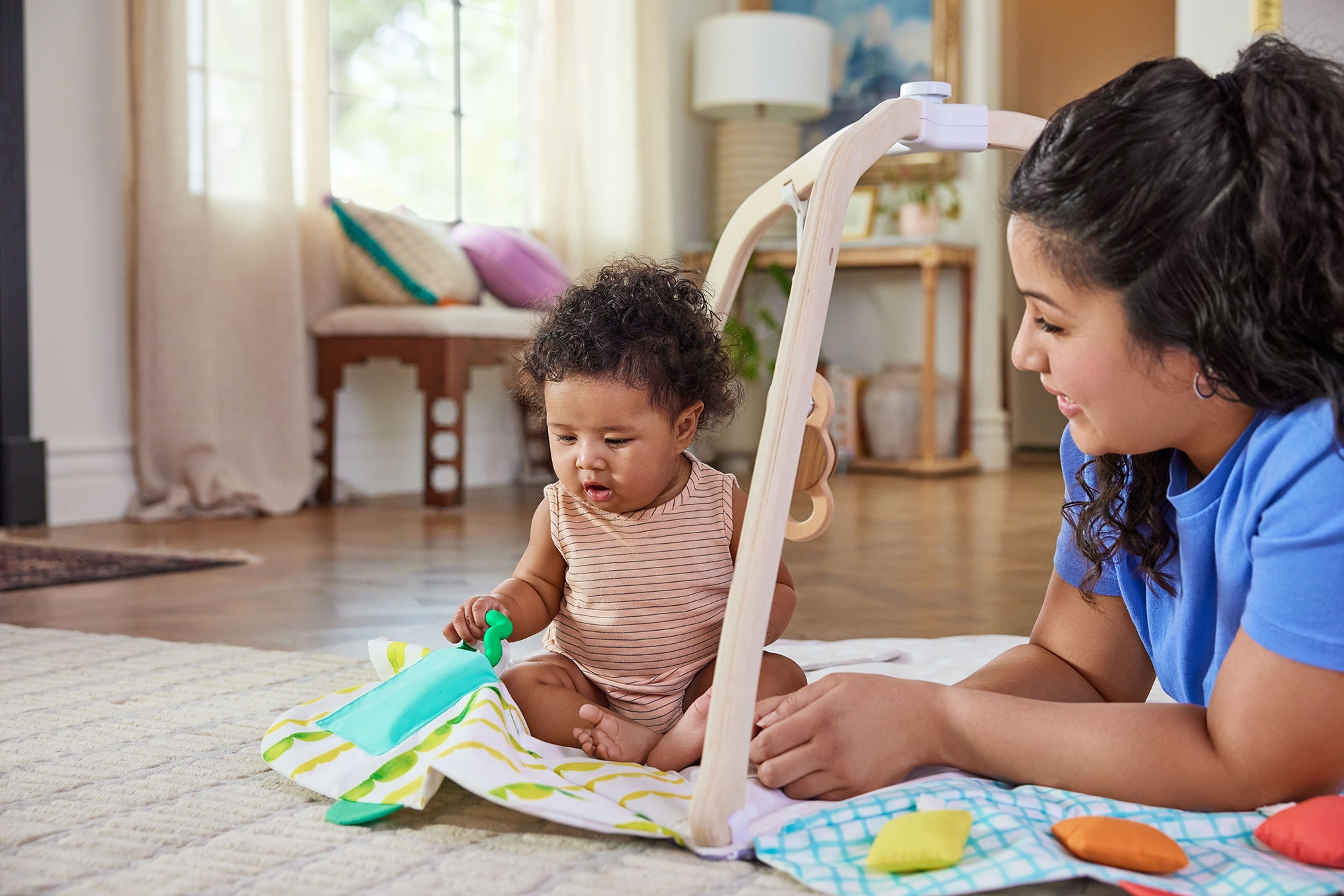 Woman and child playing on a blanket with toys in a home setting
