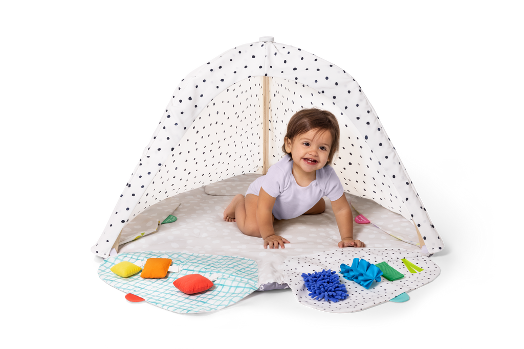 Child playing under a polka dot canopy with toys on a white background