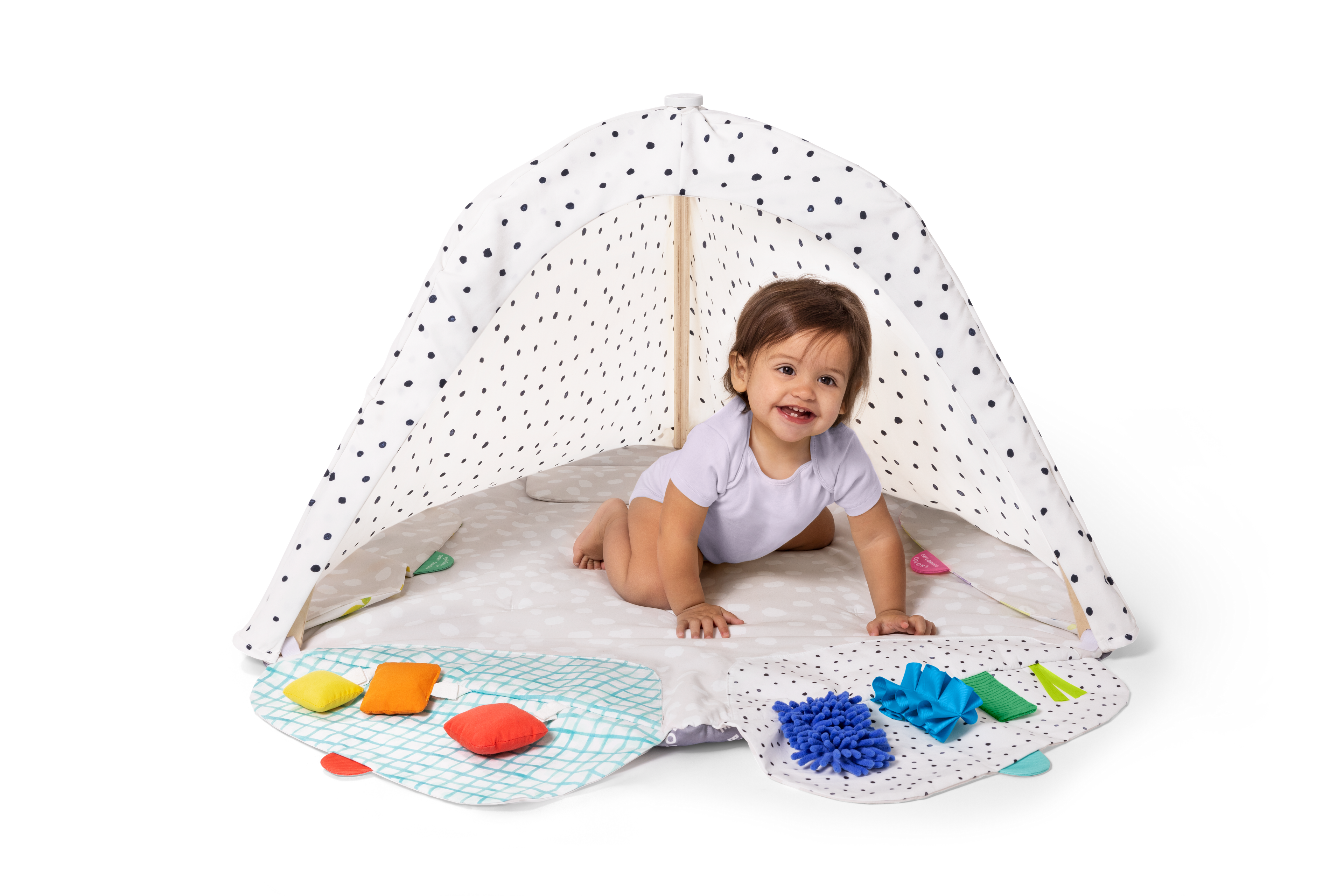 Child playing under a polka dot canopy with toys on a white background