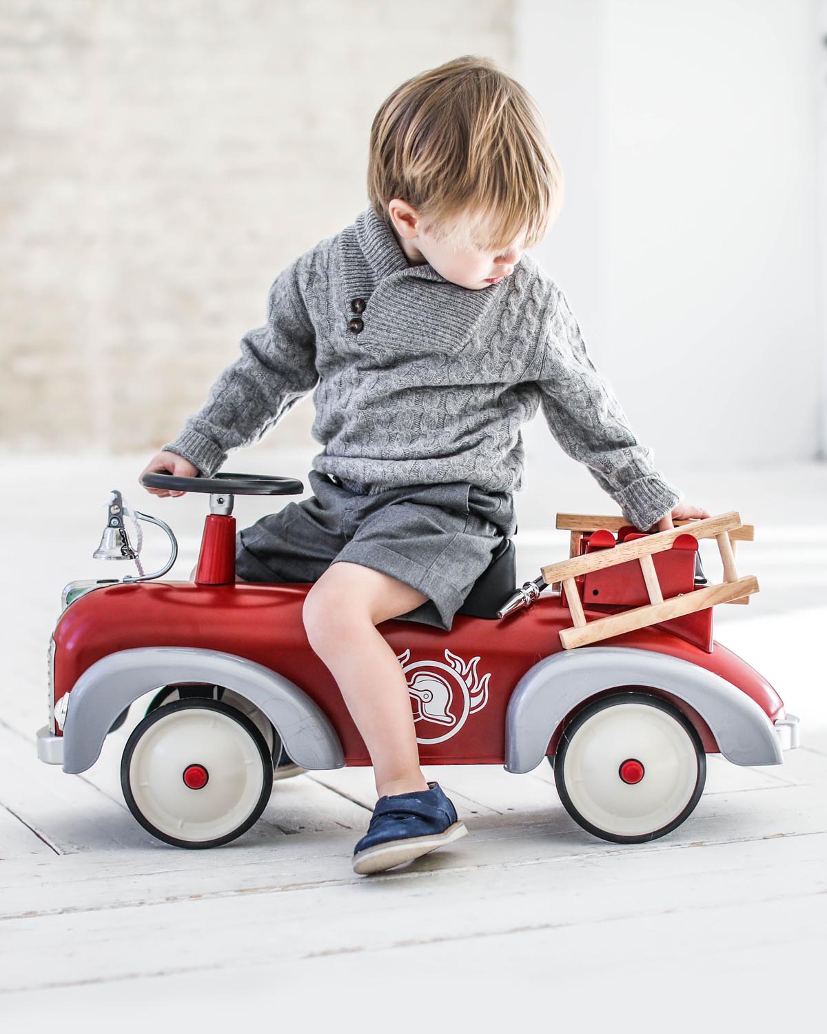 child playing with Red baghera ride-on toy fire truck with a ladder on a white background
