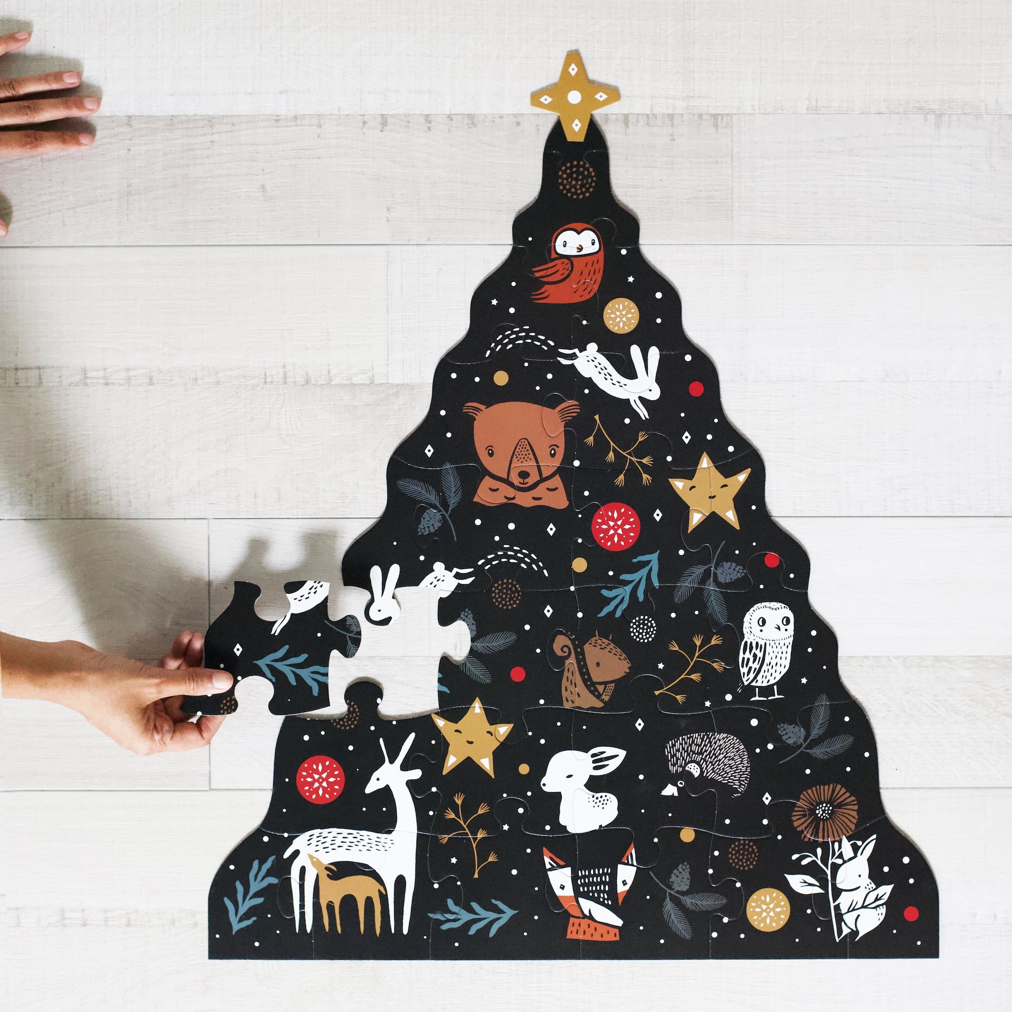 Christmas tree-shaped puzzle with animal illustrations on a wooden surface