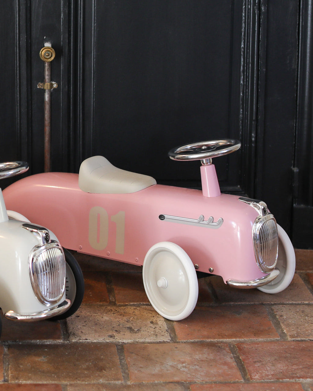 Pink baghera ride-on roadster with the number 01 on a tile surface