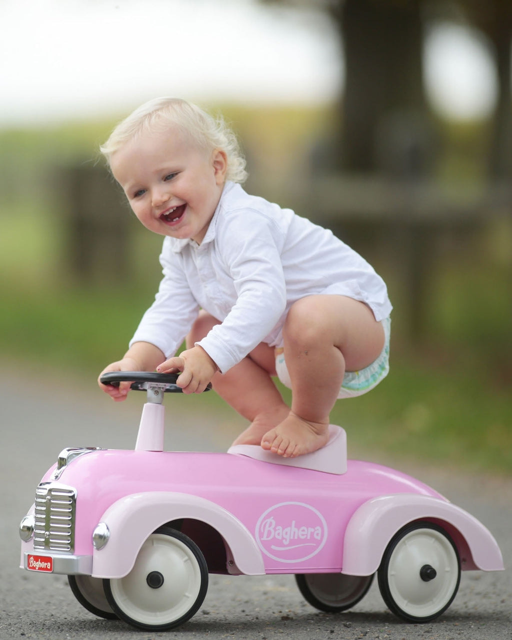 Child riding a pink baghera speedster toy car outdoors