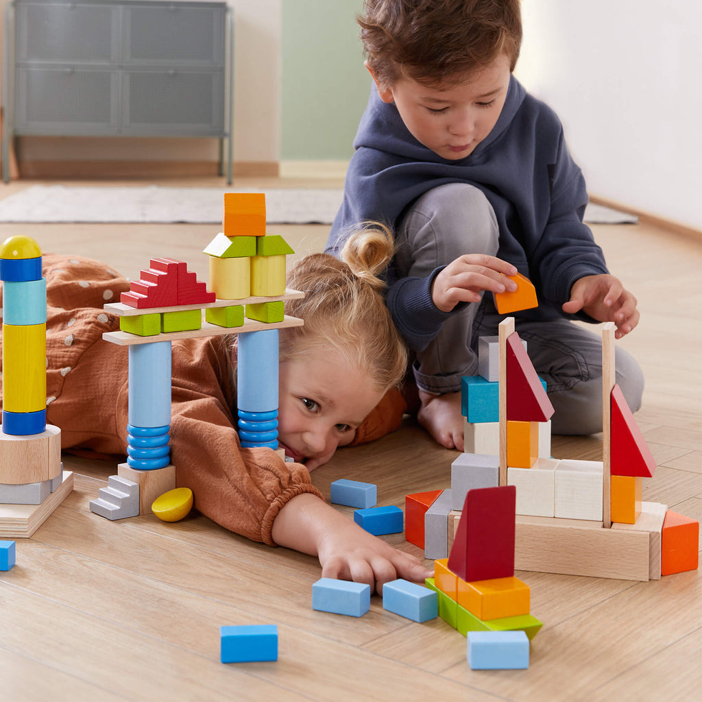 Two children playing with HABA Colored Wooden Building Blocks 85 Piece Set - Large Block Collection | HABA USA