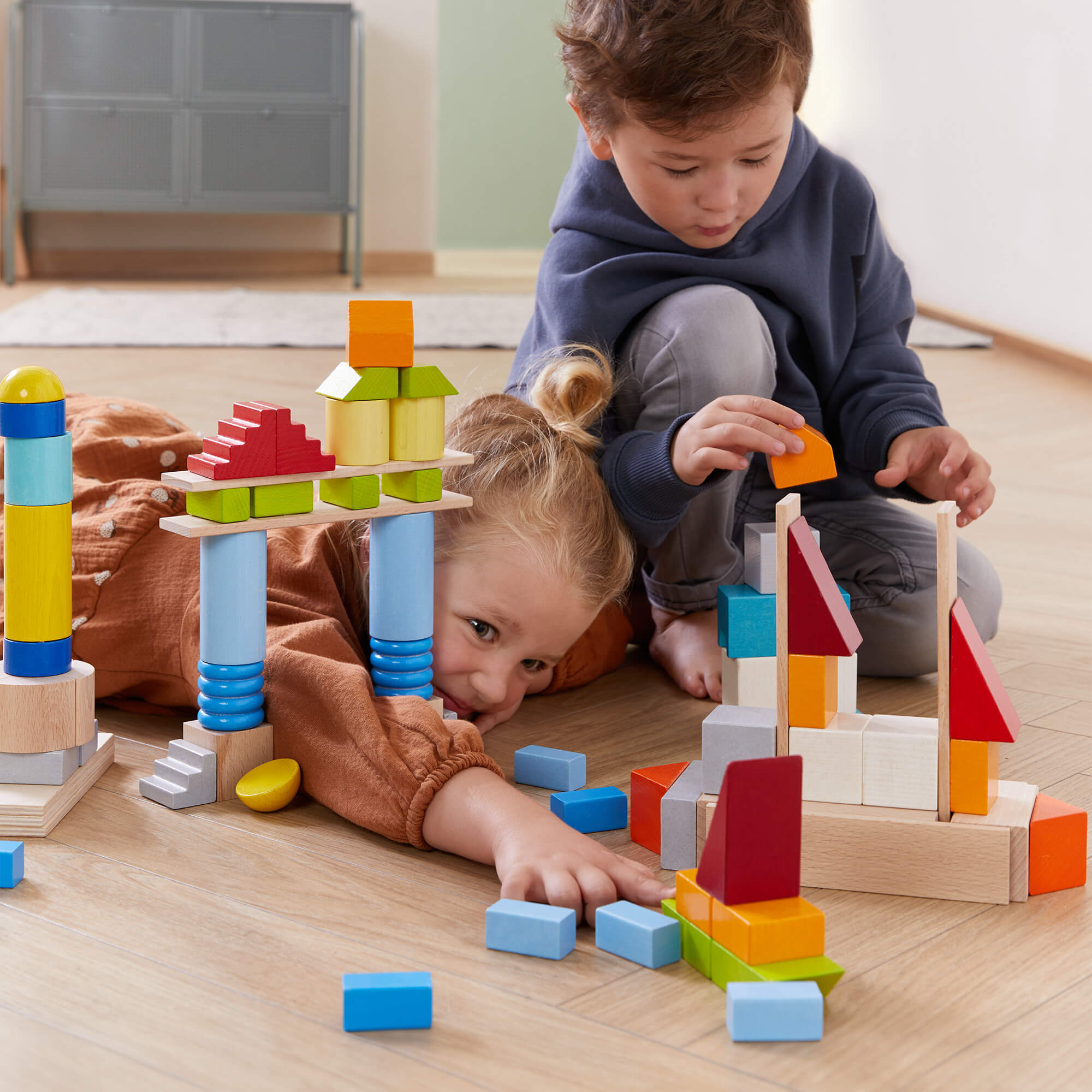 Two children playing with HABA Colored Wooden Building Blocks 85 Piece Set - Large Block Collection | HABA USA