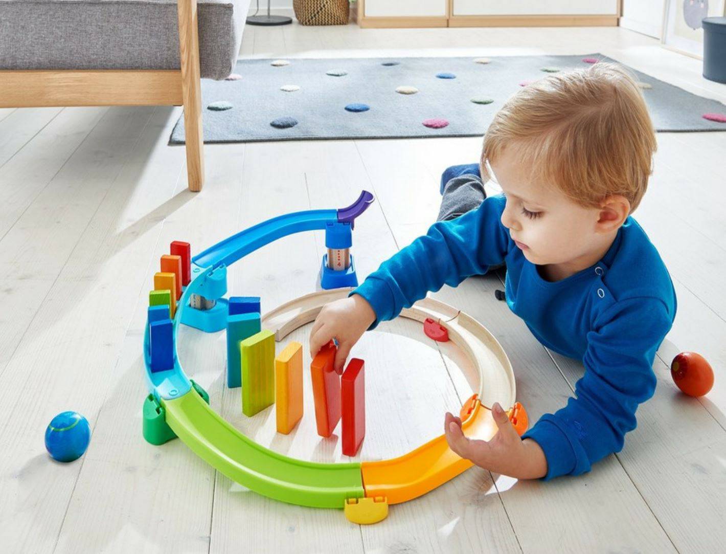 Boy playing with Haba colorful kullerbu toy track with moving balls on a light gray background