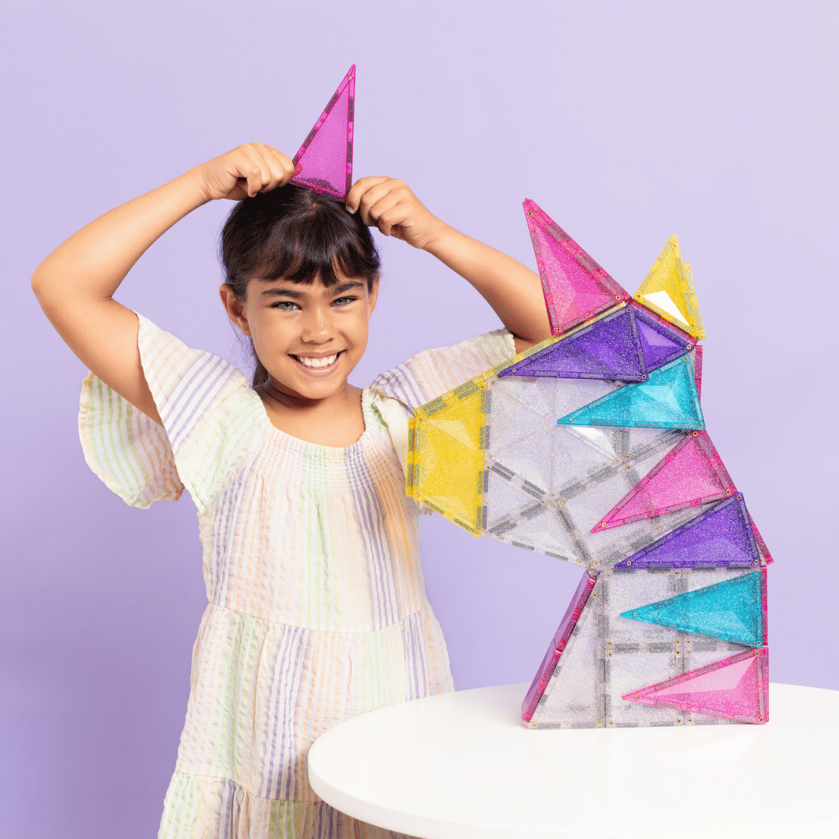 Child playing with colorful geometric toys against a purple background