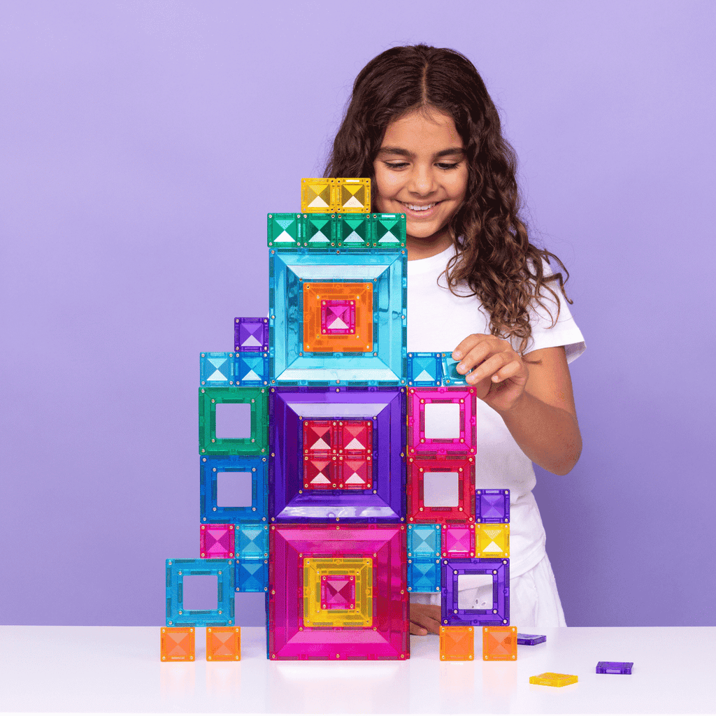 Child playing with colorful magnetic building blocks against a purple background